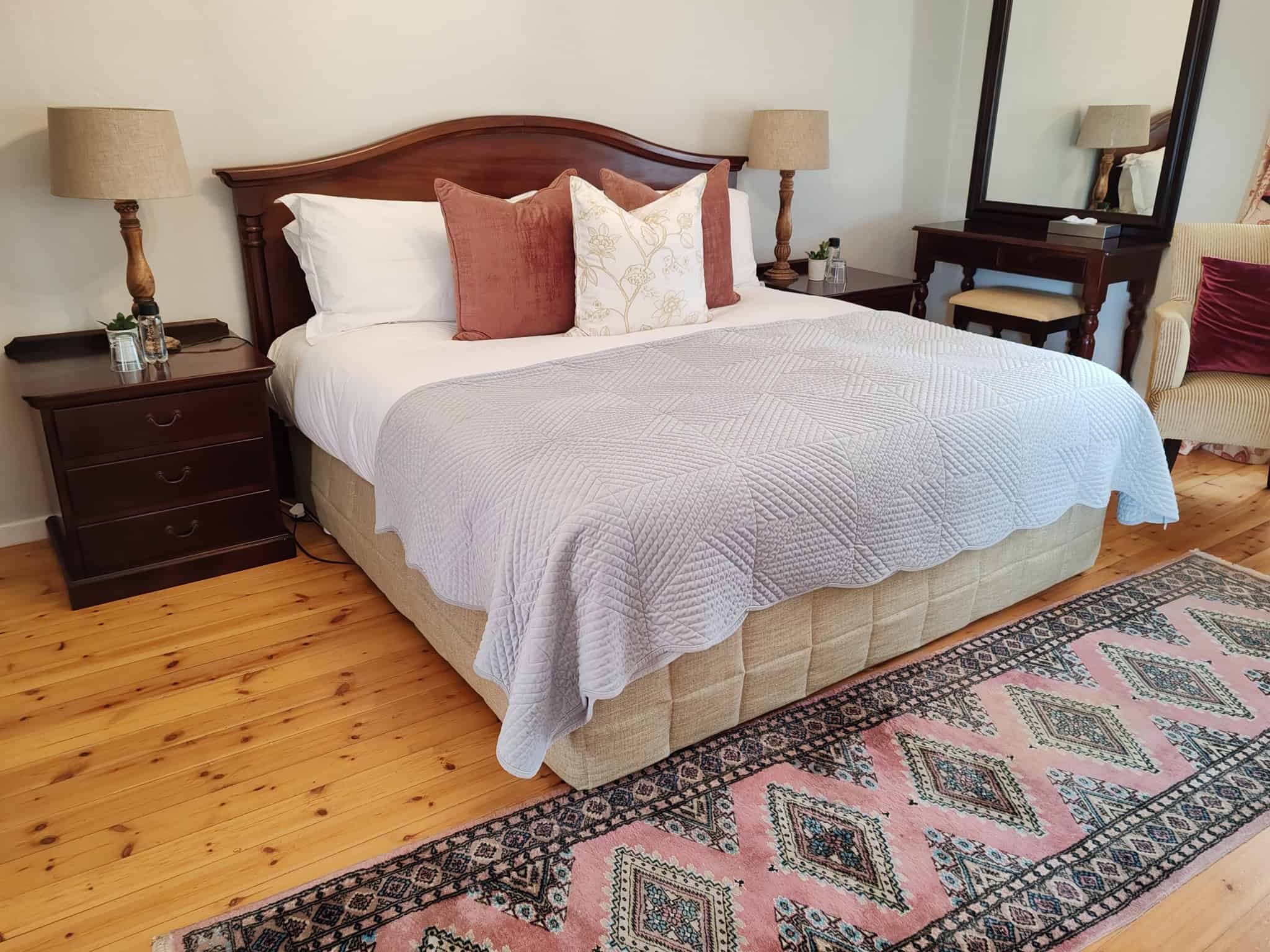 Elegant bedroom with wooden bed frame, soft pillows, and a patterned rug.
