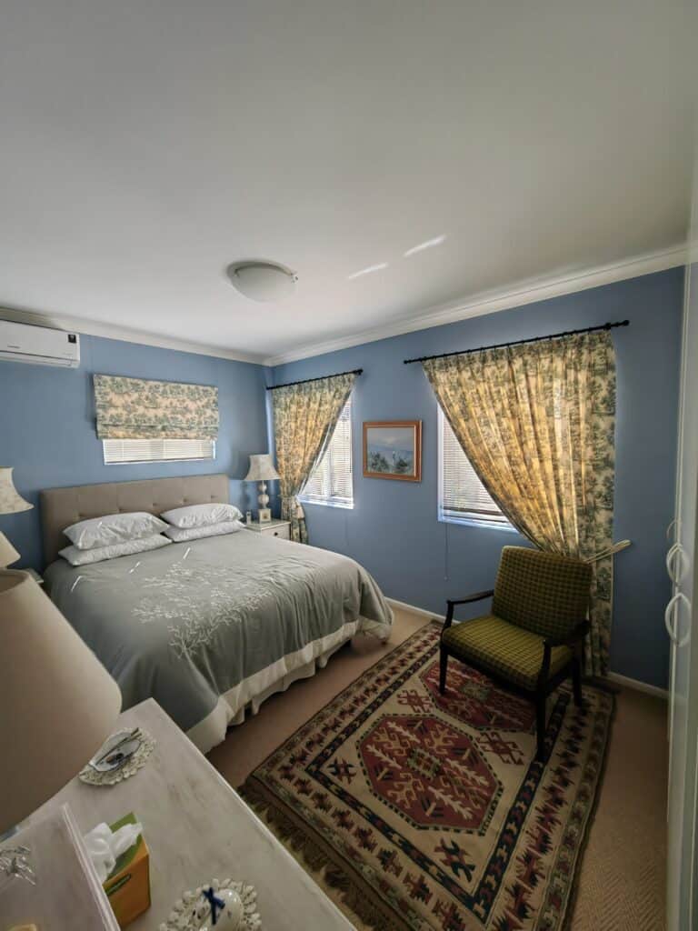 Bright bedroom with blue walls, vintage curtains, and classic furniture for a warm, inviting atmosph.