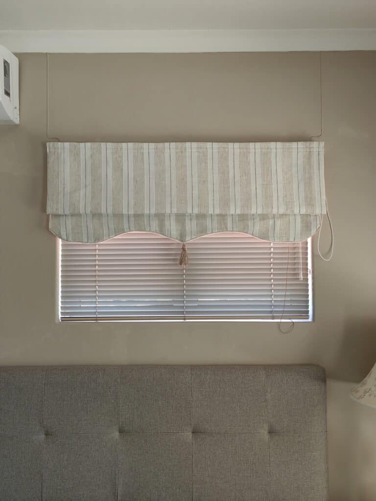 Beige window blind with striped valance and horizontal blinds, ideal for modern home interiors.