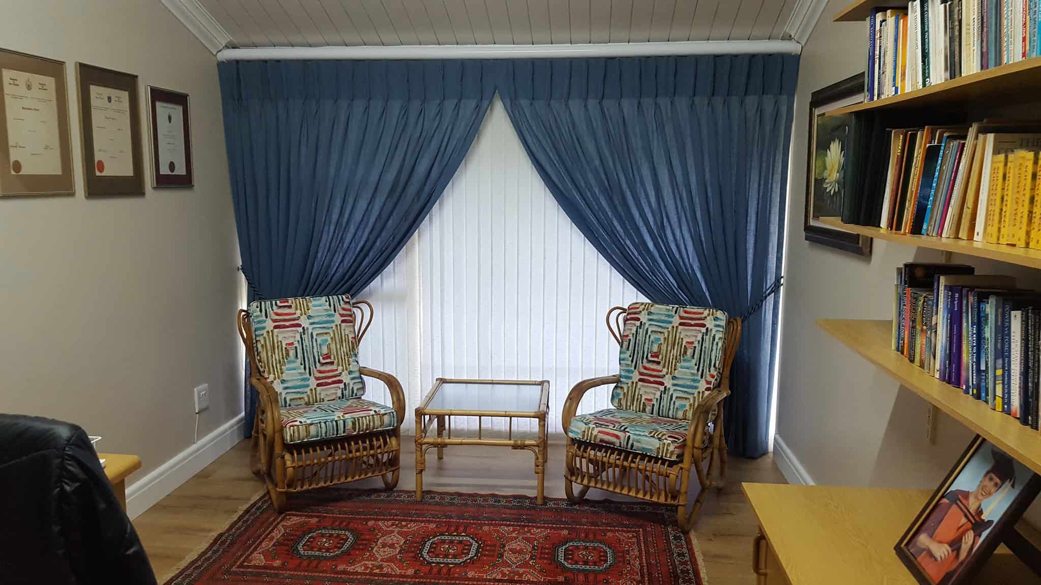 Comfortable reading corner featuring two patterned armchairs, a wooden side table, and a well-stocke.