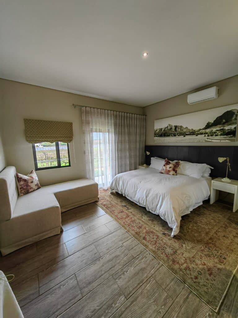 Bedroom interior with beige walls, large window, and cozy furnishings.